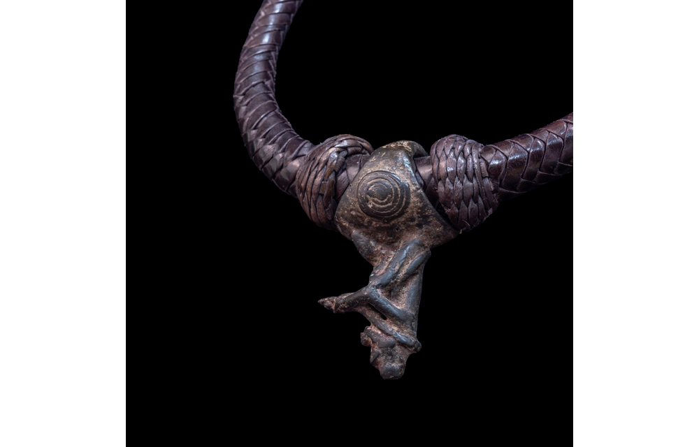 Braided leather necklace with small antique bronze pendant.