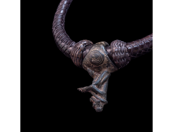 Braided leather necklace with small antique bronze pendant.