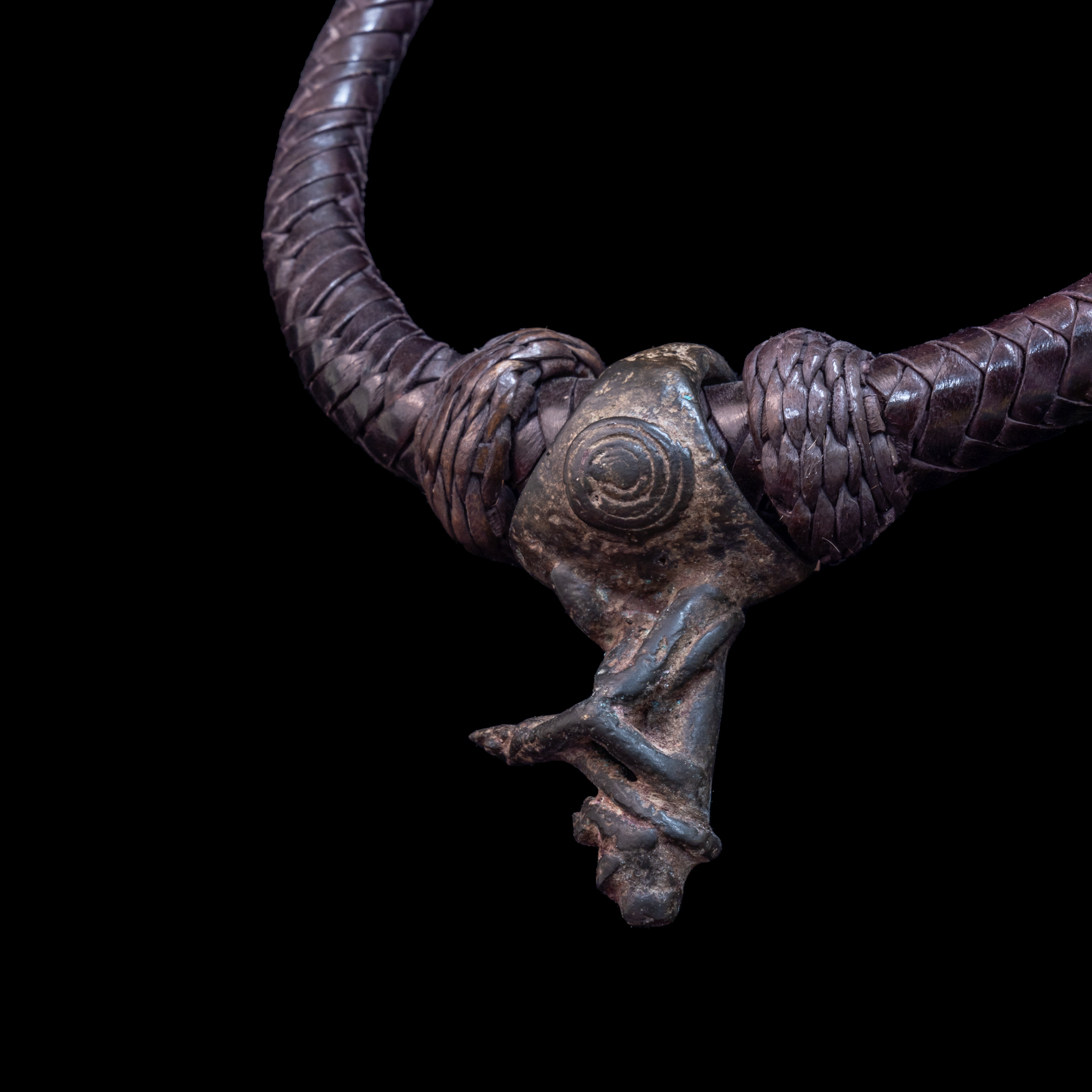 Braided leather necklace with small antique bronze pendant.