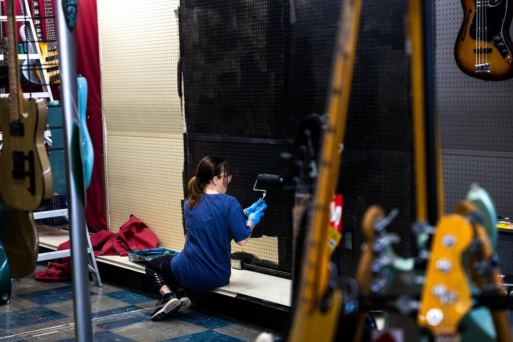 Roxy Music repair tech working on a red electric guitar at the repair bench