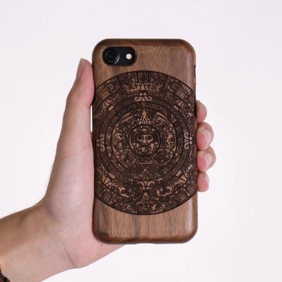 Hand holding a wooden phone case with an intricate circular engraving by a FLUX Beambox laser cutter.