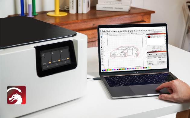 FLUX Ador sitting on a whote wooden table next to an open laptop showing the LightBurn software. A file of a car is shown on screen.