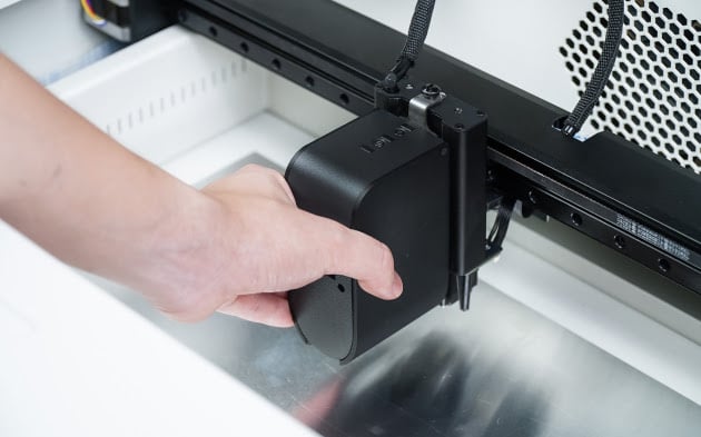 Close-up of a hand taking the print module out of the Ador machine.