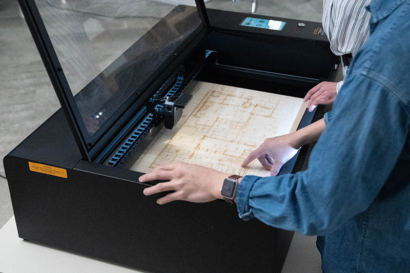 An open FLUX HEXA laser cutter with a 3d engraved floorplan on wood