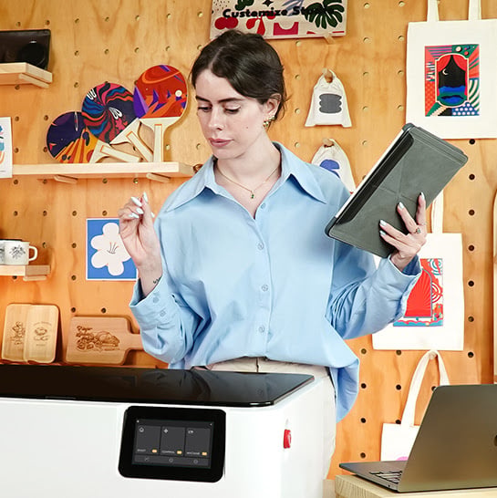 A woman looking at het FLUX Ador while holding a tablet and a pen.