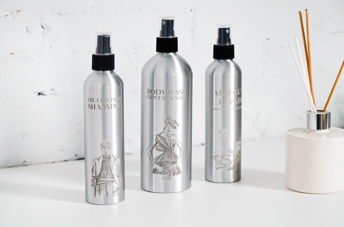 Three aluminum spray bottles with engraved designs by the FLUX Ador rotary module.