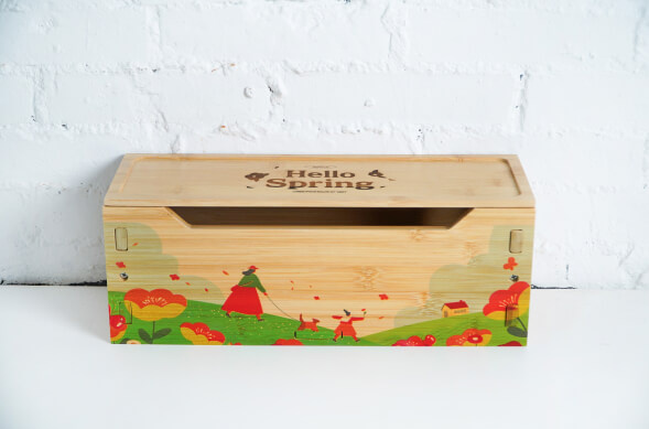 Wooden box with a colorful landscape printed on the front and an engraving of 'Hello Spring' on the lid.