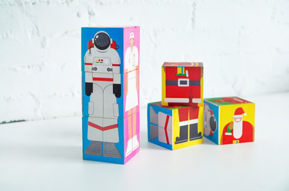 Wooden puzzle block stacked on top to show a printed design of an astronaut and a nurse. Three unassembled blocks are placed next to it.