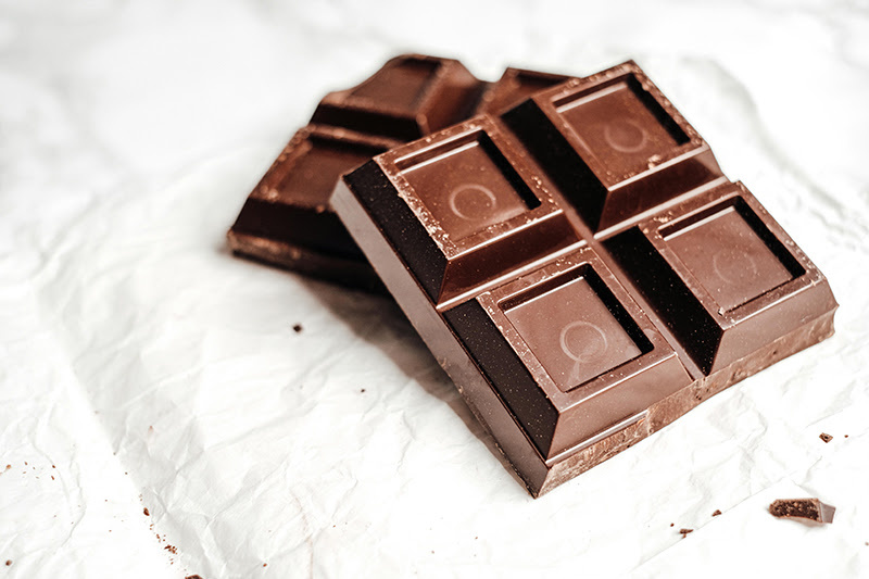 Piece of chocolate with four squares on a white paper background
