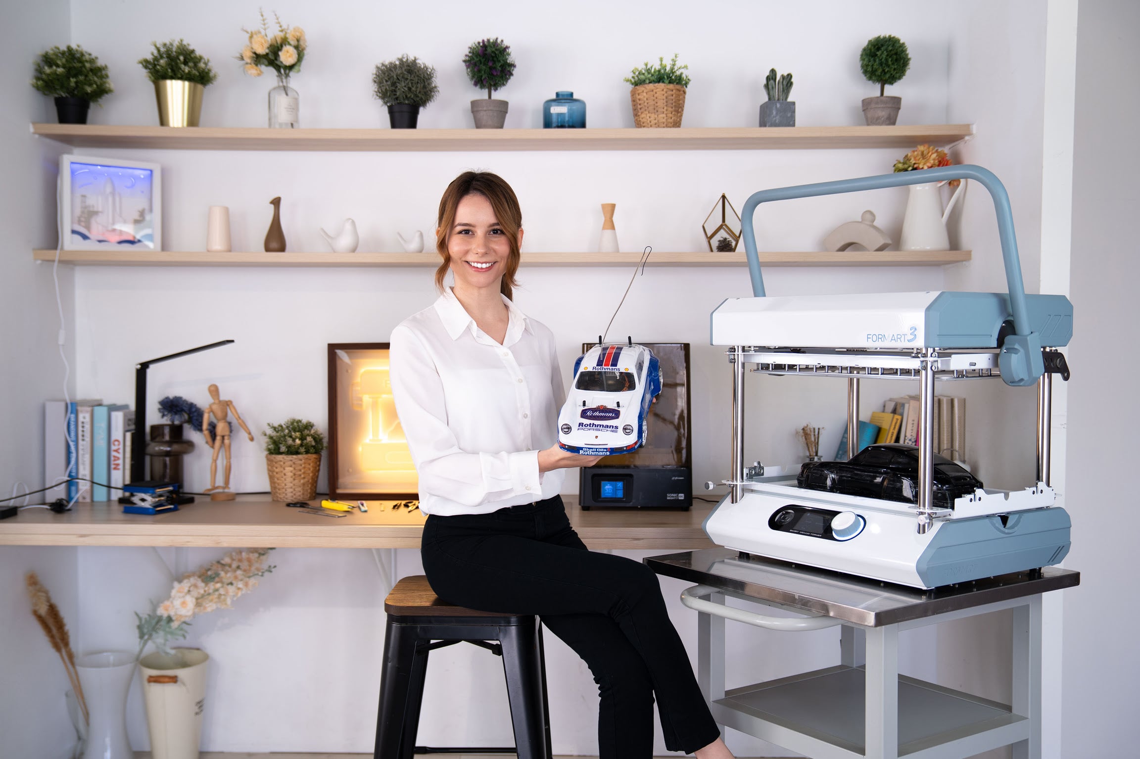 Woman holding an RC car with a vacuum formed body. She is sitting next to the FORMART 3 vacuum former.