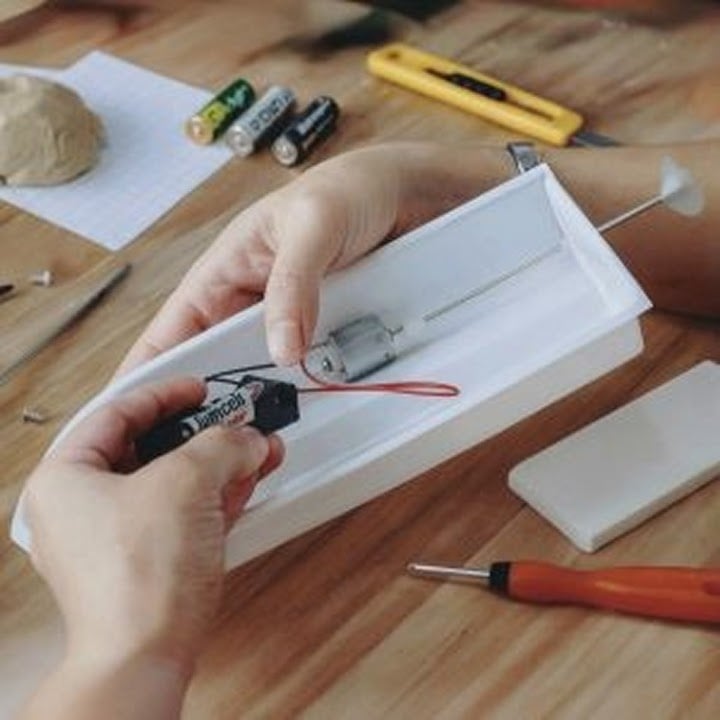 Person holding a vacuum formed hull of a boat to create an RC boat.