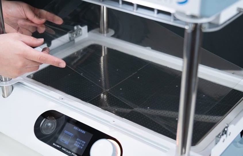 Hands placing a material sheet inside the FORMART 3.