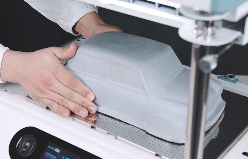 Hands placing a master mold of a car inside the FORMART 3.