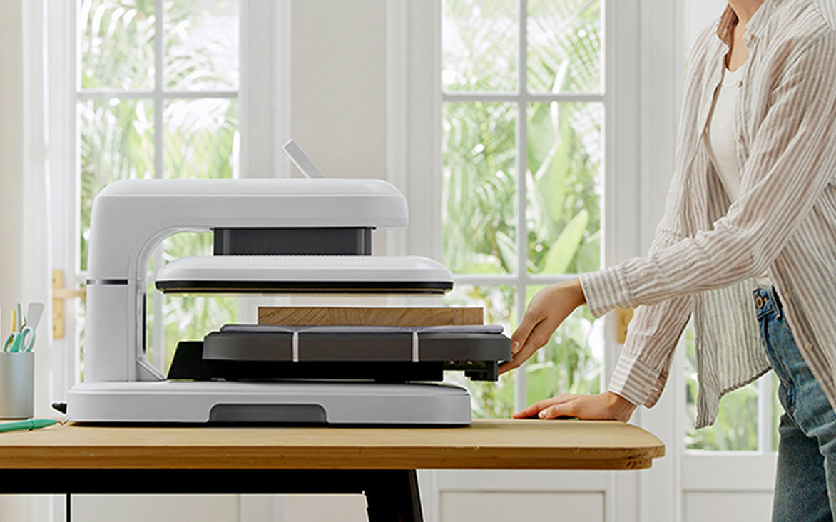 LOKLiK ImPress™ Auto 2-Smart in Daisy White on a table. A woman is pulling out the ironing board. On the board is a 4.5 cm piece of wooden board.