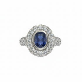RYAN GEMS INC (Y)18KW 1.50SA 1.40DIA  OVAL BEVEL SET SAPPHIRE CENTER STONE SURROUNDED BY CLUSTERS OF DIAMONDS