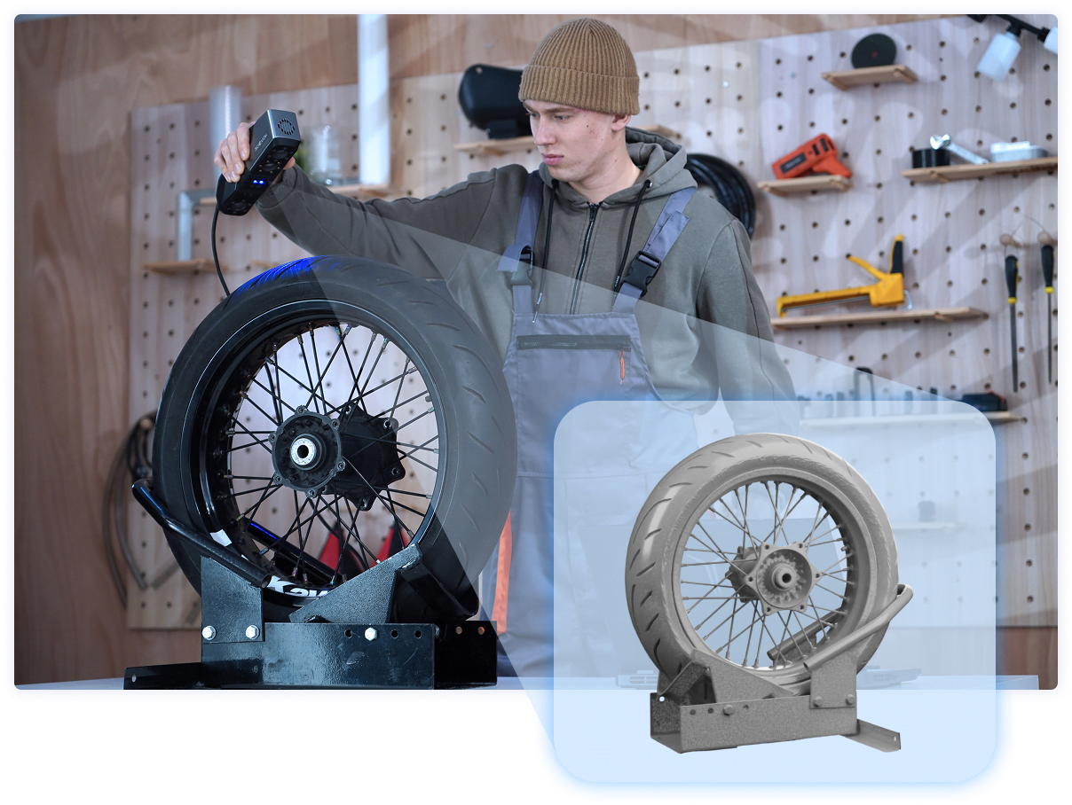 Man in a car workshop holding a 3DeVOK MT and 3D scanning a wheel standing upright with the blue laser line mode. There is a cutout of a 3D render of the wheel.