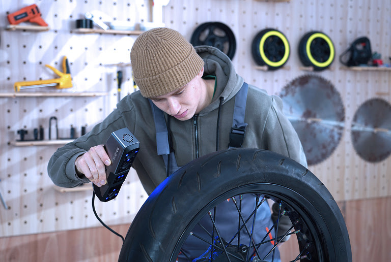 A man in a car workshop 3D scanning a wheel