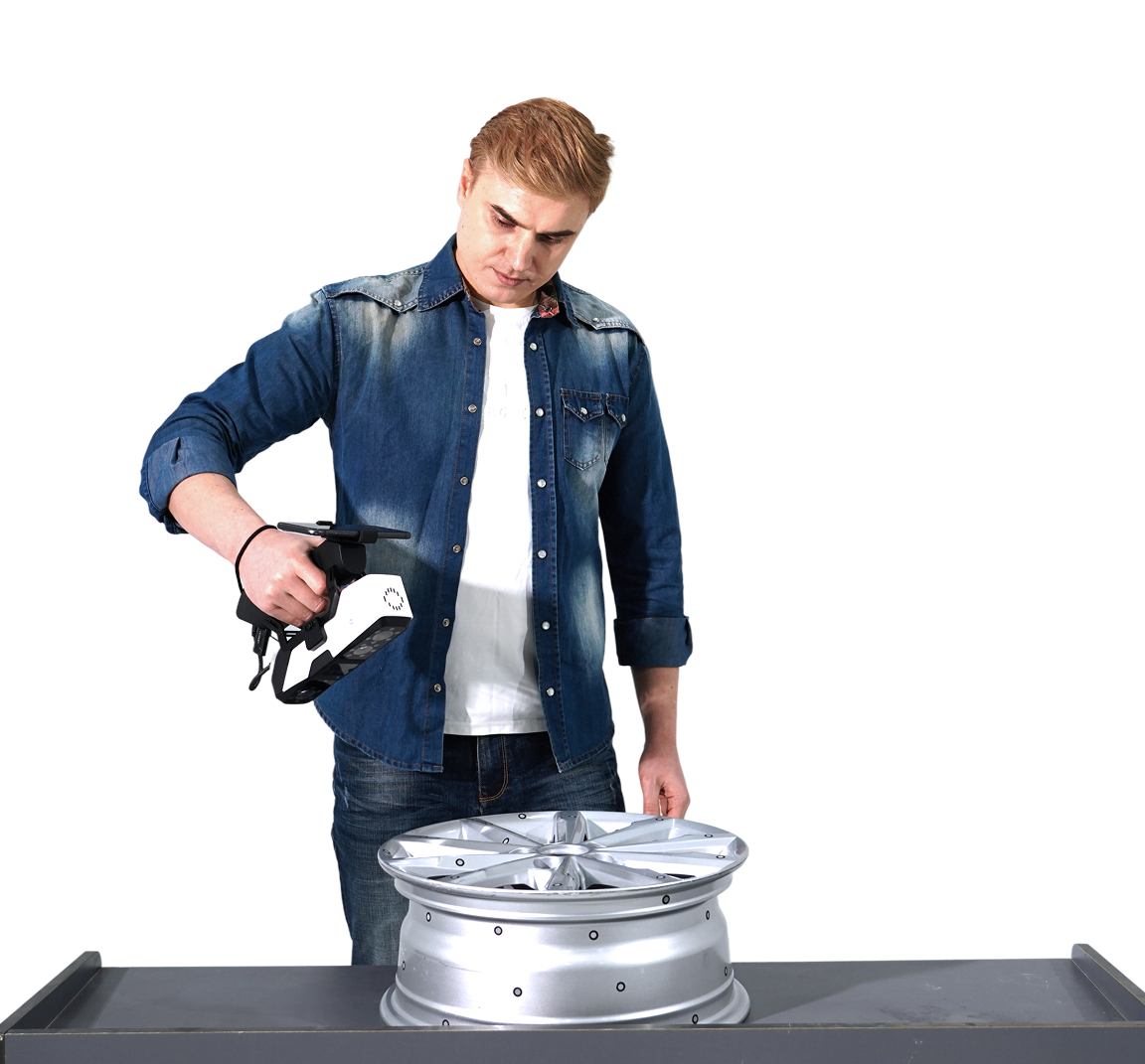 Man holding the 3DeVOK MQ with the optional wireless handle and scanning a car rim on a table.