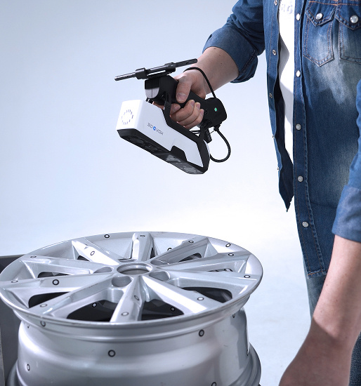 Man holding the 3DeVOK MQ with the optional wireless handle and scanning a car rim.