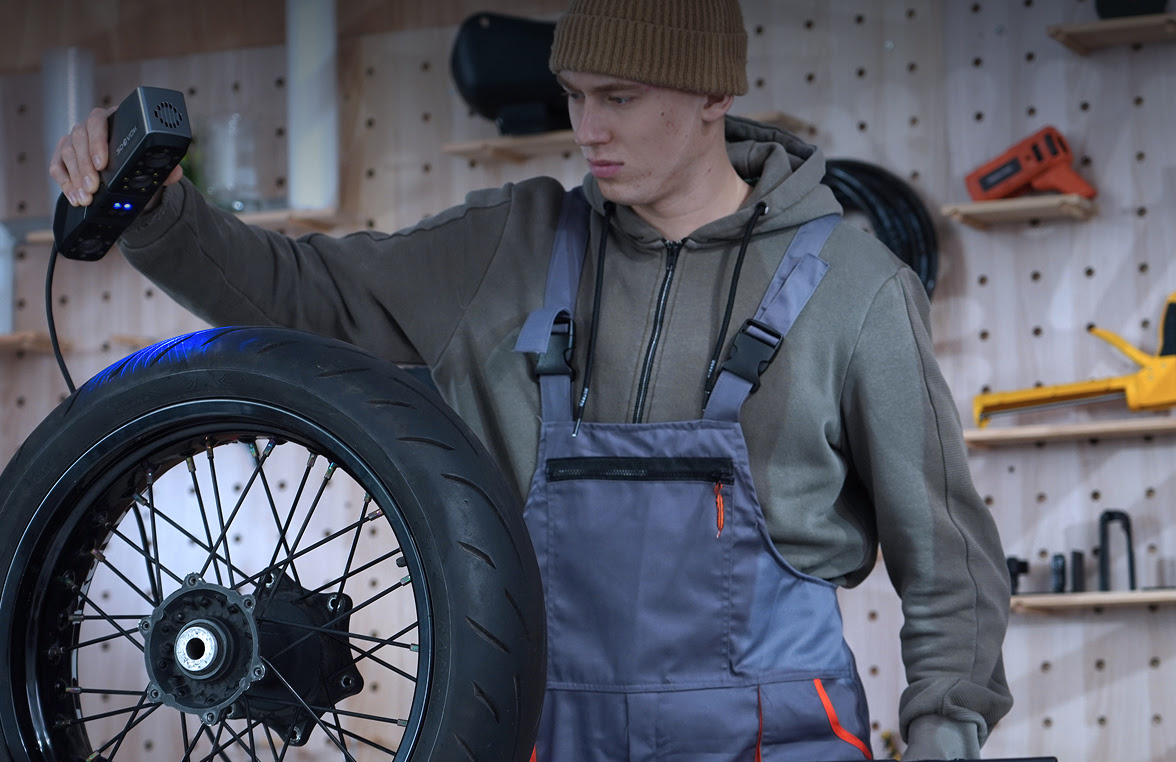 Man in a car workshop holding the 3DeVOK MT and 3D scanning the weel of a motorccyle