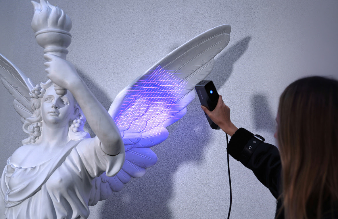 Woman holding the 3DeVOK MT and scanning the wing of an angle statue with the 34 blue laser line mode.