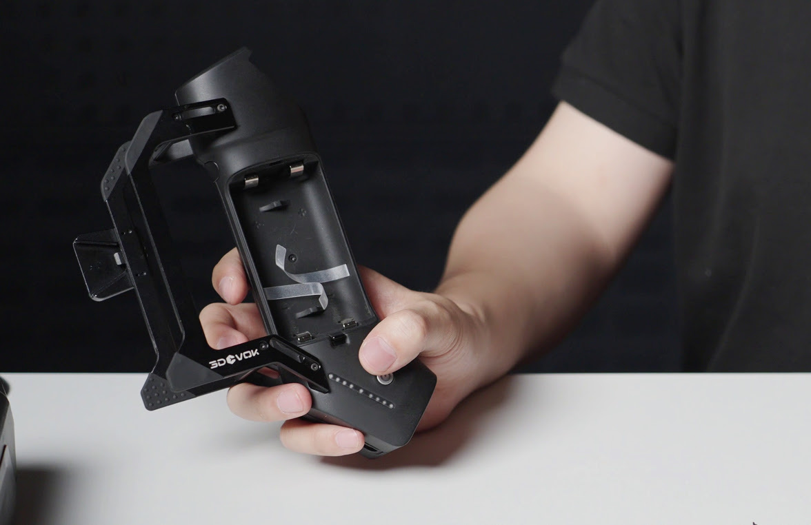Hand holding the Airgo handle. The battery compartment is opened and the handle has no batteries inside.
