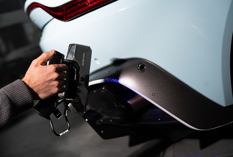 Hand holding the 3DeVOK MT Gen2 with the Airgo Wireless handle, 3D scanning the bumper of a light blue car without markers.
