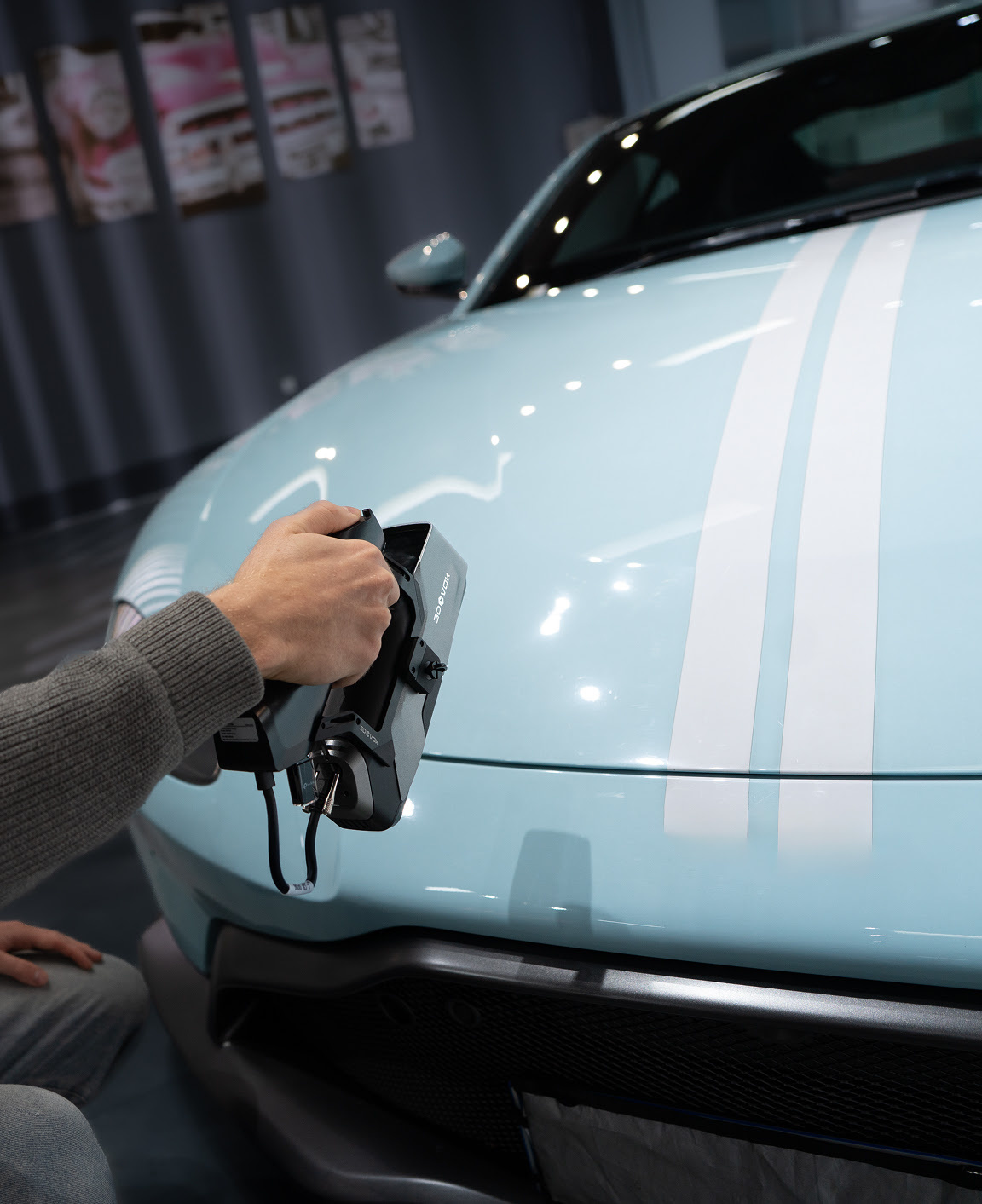 Hand holding the 3DeVOK MT Gen2 with the Airgo Wireless handle, 3D scanning the hood of a light blue car without markers.