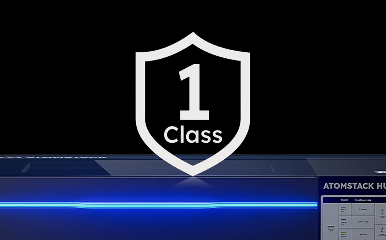 Frontal view of an AtomStack Hurricane with the blue led strip glowing. On top is an illustration of a white shield and the text Class 1