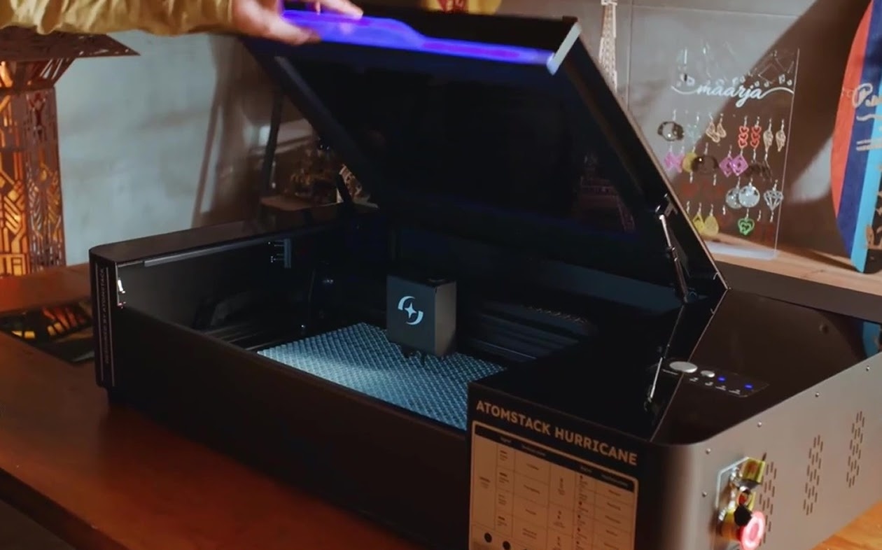 Man opening an AtomStack Hurricane standing on a table.