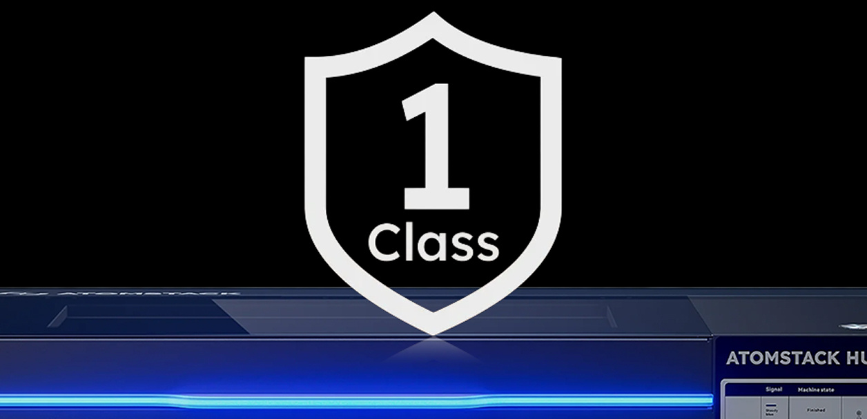 Frontal close-up of the AtomStack Hurricane against a black background. On top is an illustration of a shield containing 'Class 1'