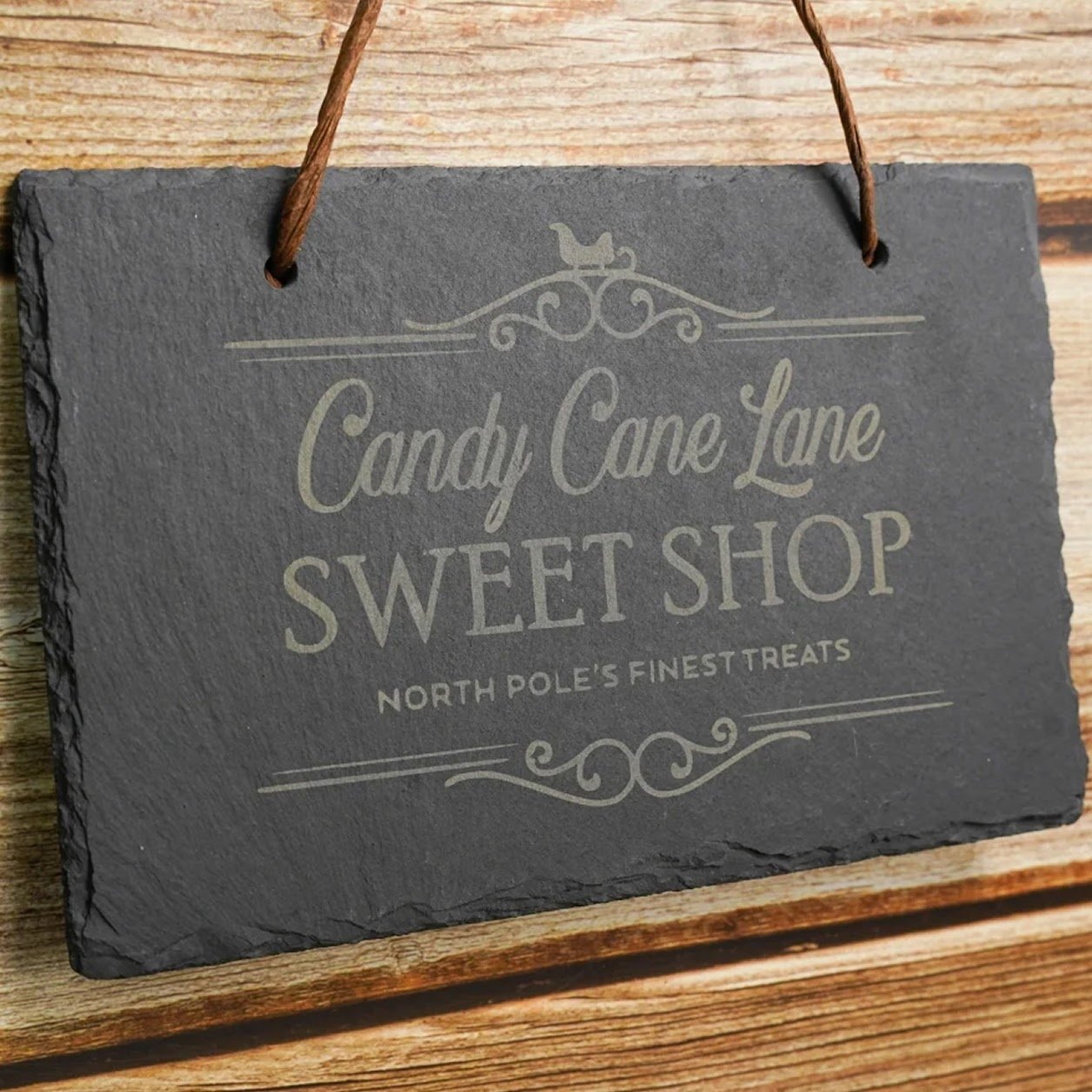 Stone sign with a laser engraved design stating Candy Cane Lane Sweet Shop
