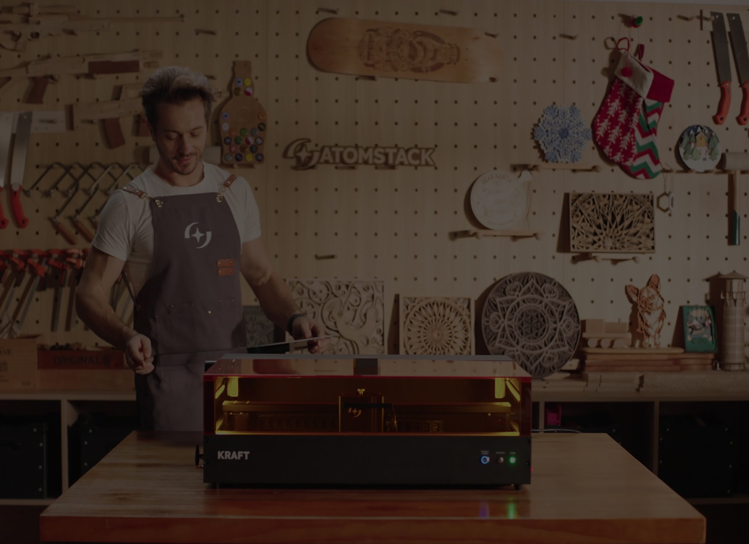 Man in a workshop admiring a lasercut piece he just made. He is standing behind an AtomStack Kraft.