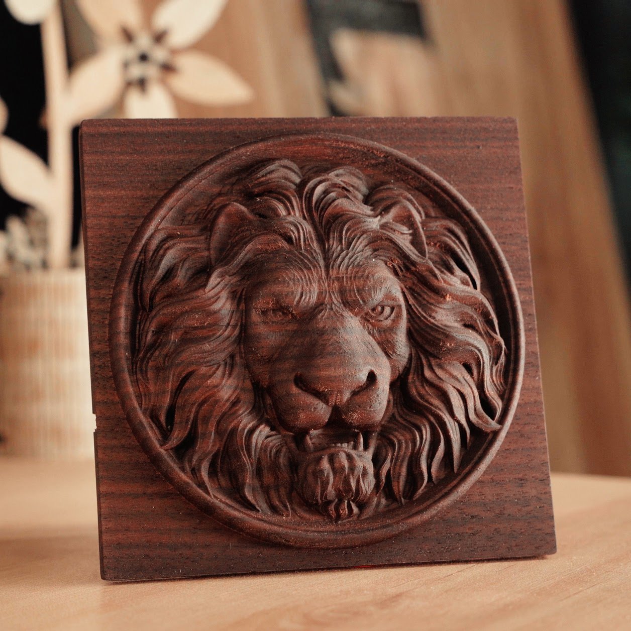 Square piece of black walnut wood with a circular milled design of a lion s head