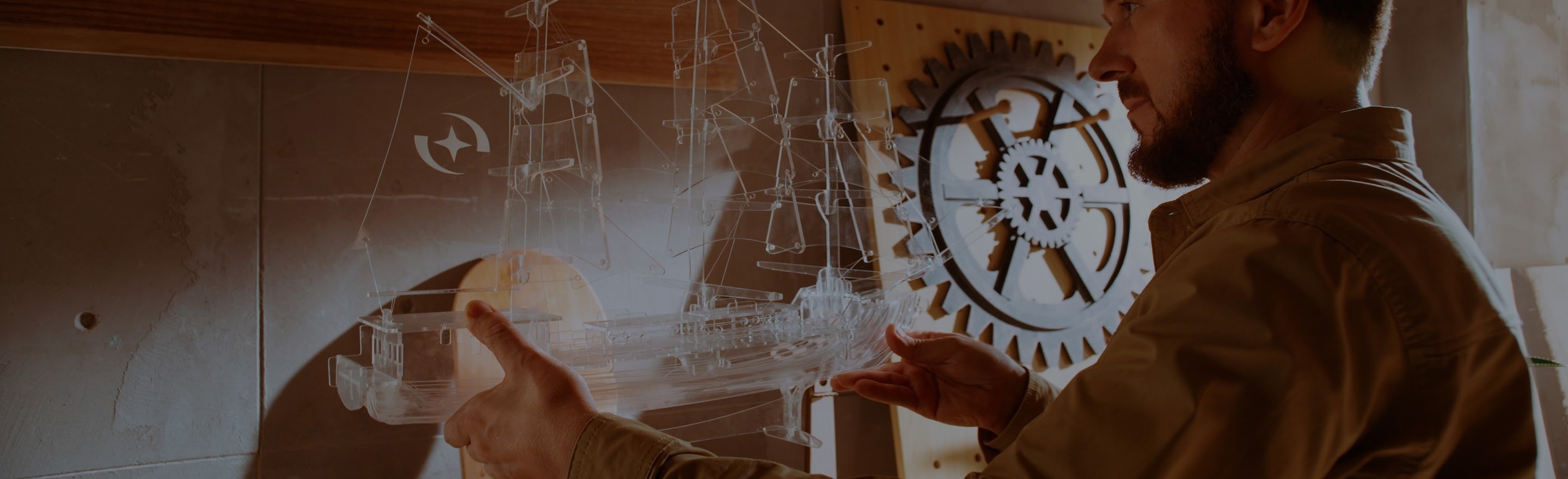 Man holding and admiring a lasercut model of a ship made from clear acrylic