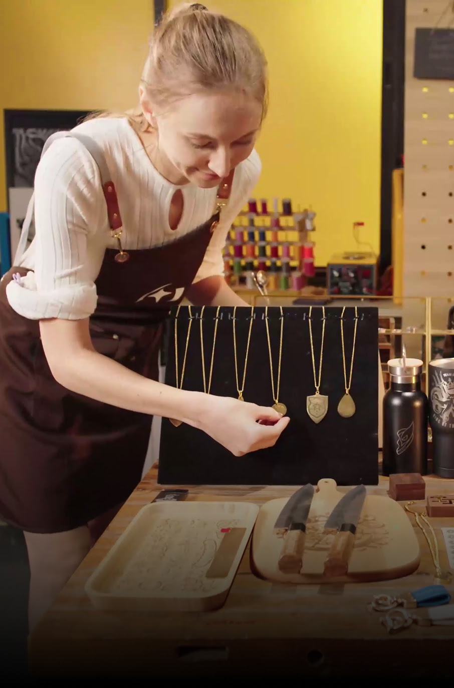 Woman arranging necklaces on a stand in her shop.