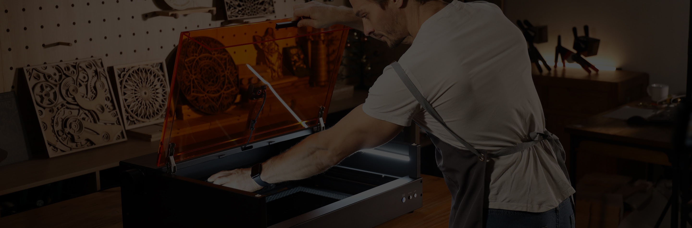 Man in a workshop opening an AtomStack Kraft and reaching for the dual laser module.