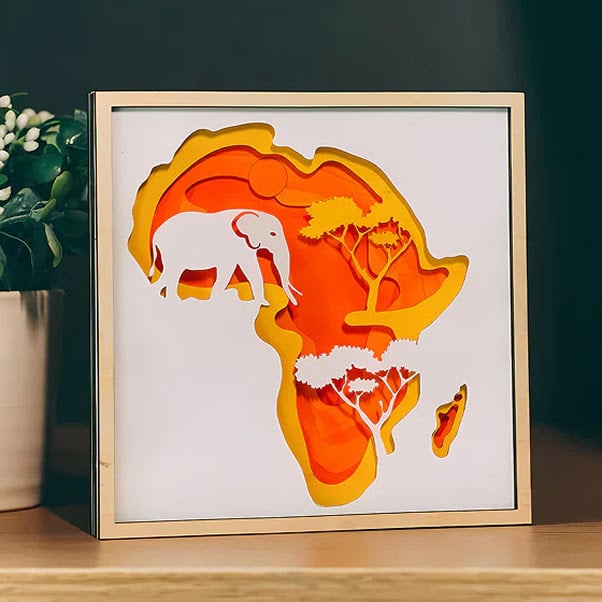 Multi-layer papercut design of continental Africa with an elephant and trees.