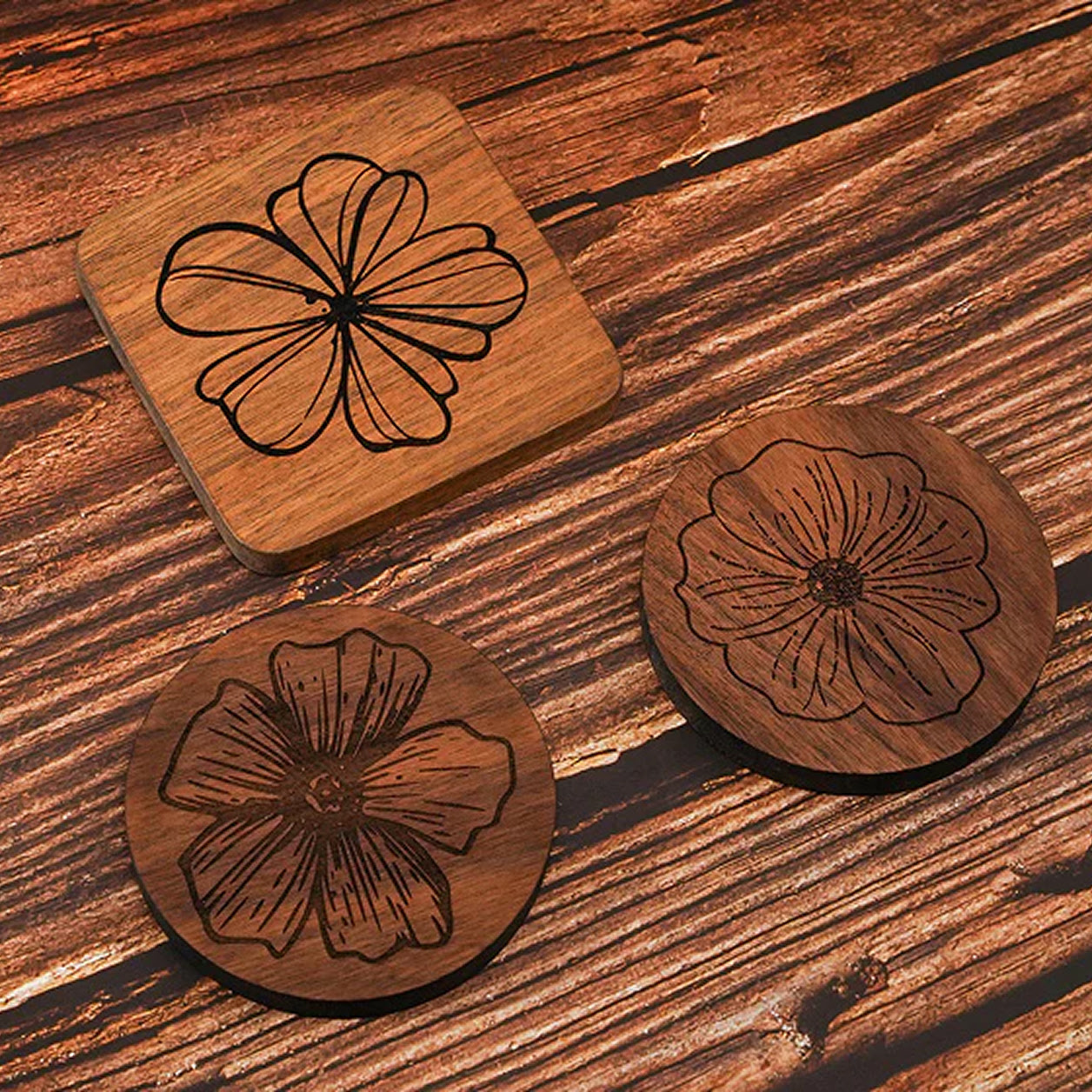 Three wooden coasters with a design of an engraved flower