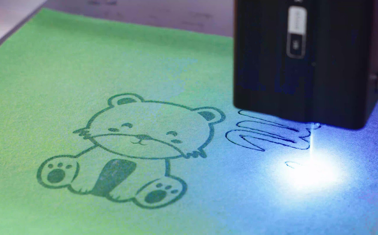 Close-up of the diode laser module engraving and cutting a piece of green felt.