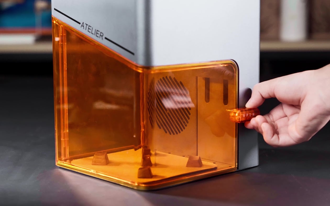 Hand opening the door of the AtomStack Atelier