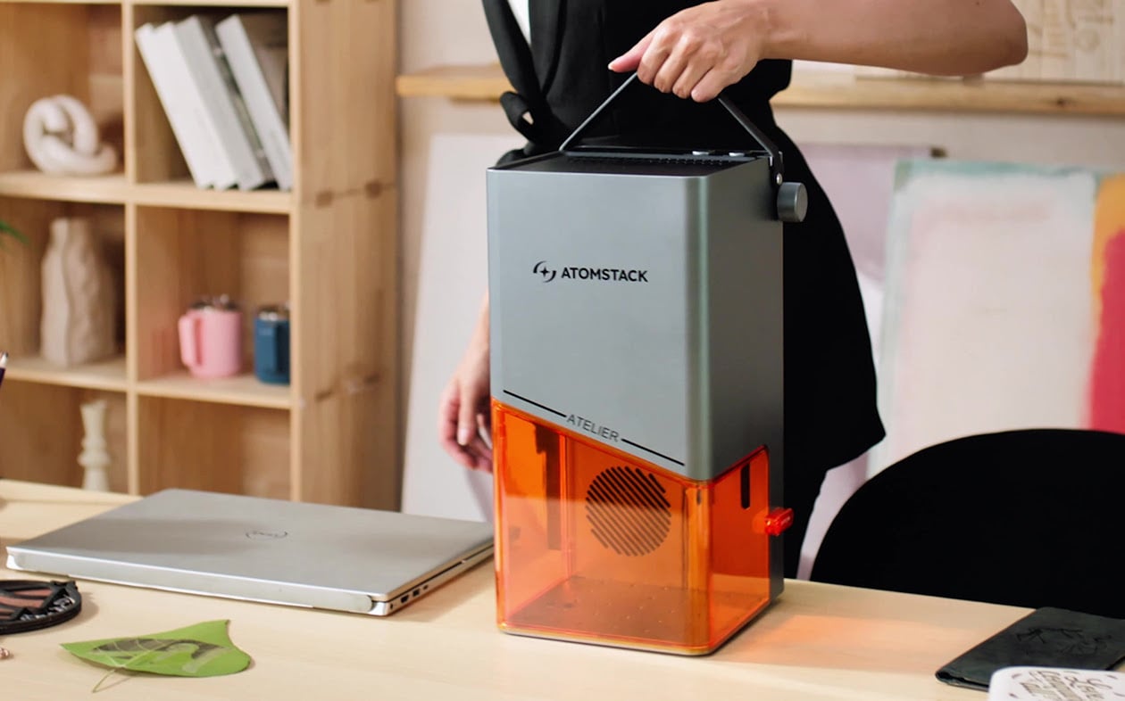 Woman picking up the AtomStack Atelier at the handle.