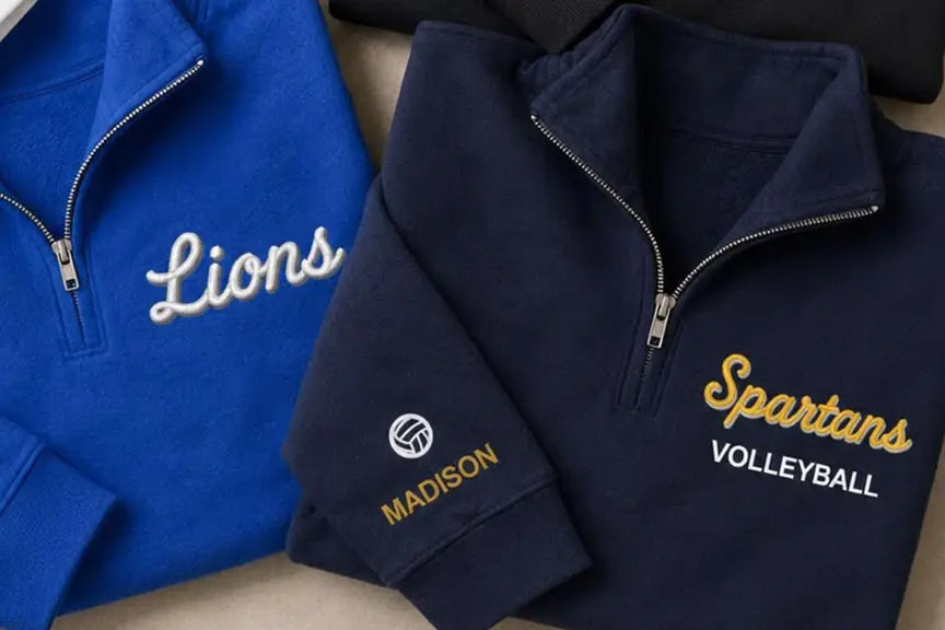 Custom embroidered quarter-zip fleece sweatshirts with team logos and sleeve personalization produced on a BAi commercial embroidery machine