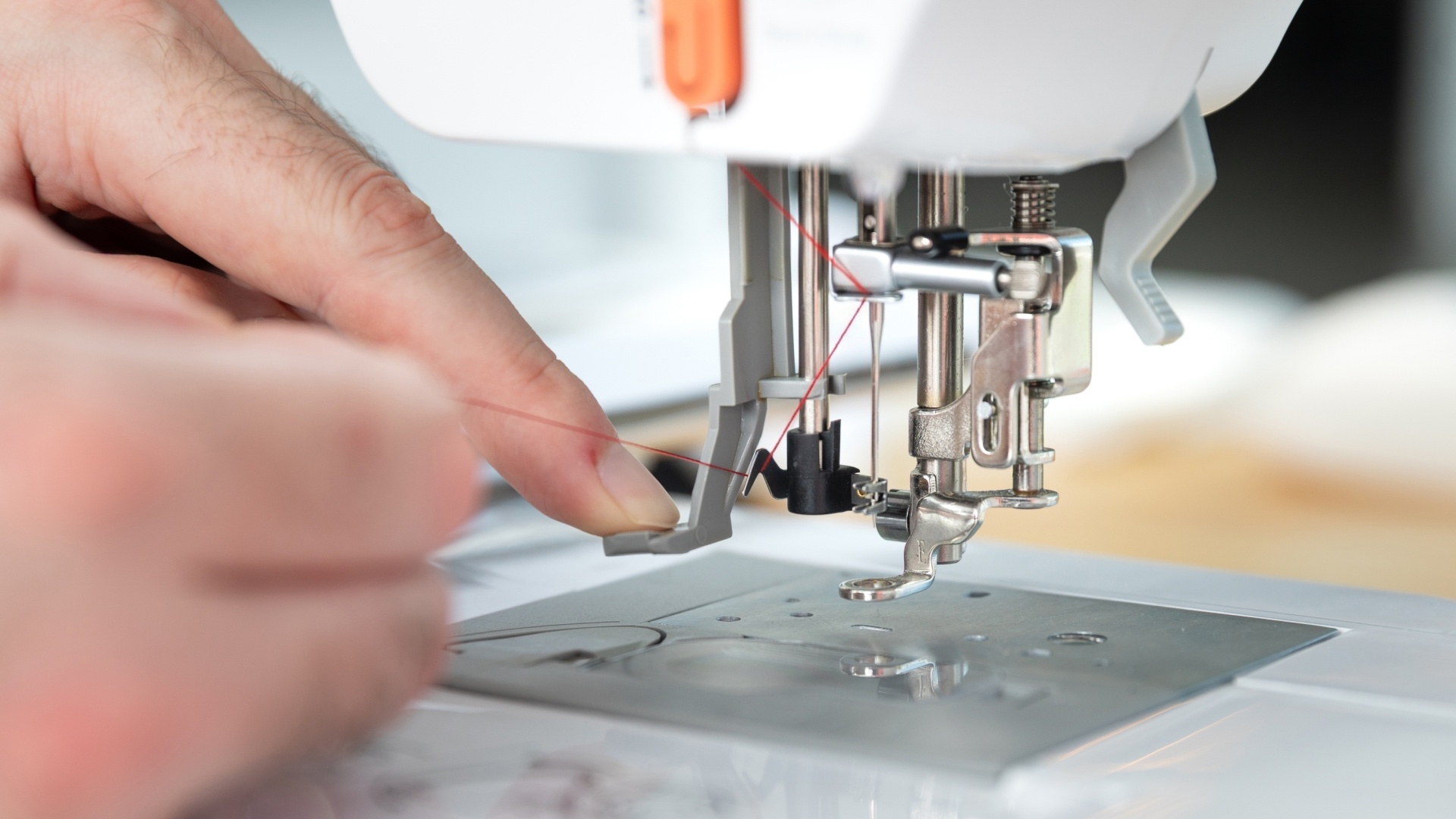 Press the handle to lower the hook and engage the needle threader