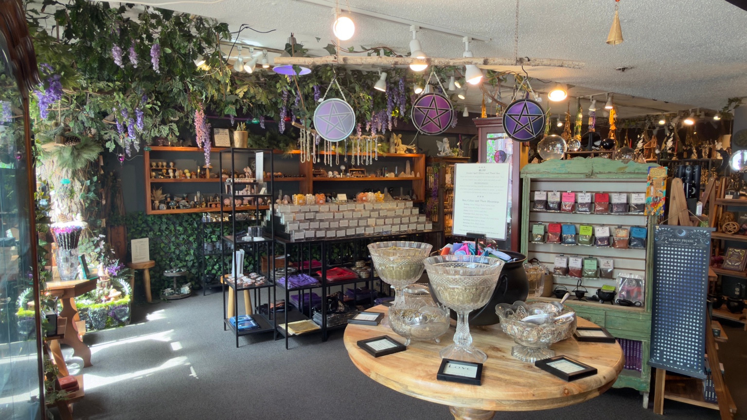 A bright view inside Enchanted, with herbs, crystal bowls and shop shelves.