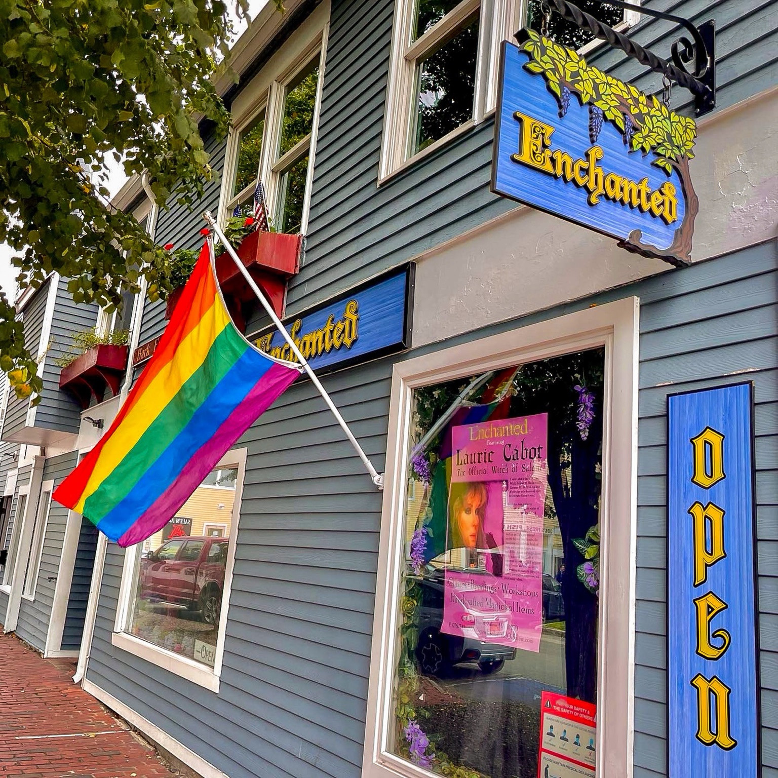 Enchanted storefront, with its hanging sign and rainbow flag.